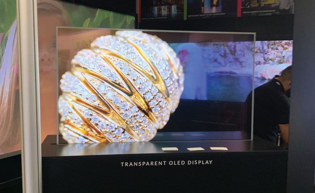 LG transparent OLED display showing a diamond jewelry close-up at an exhibition