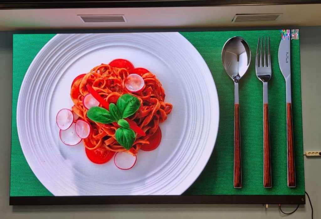 Front view of a wall-mounted Titan all-in-one LED display showing high-detail food photography